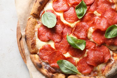 Tasty pepperoni pizza with basil on light grey table, top view