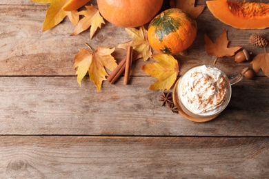 Photo of Flat lay composition with cup of pumpkin spice latte and space for text on wooden table