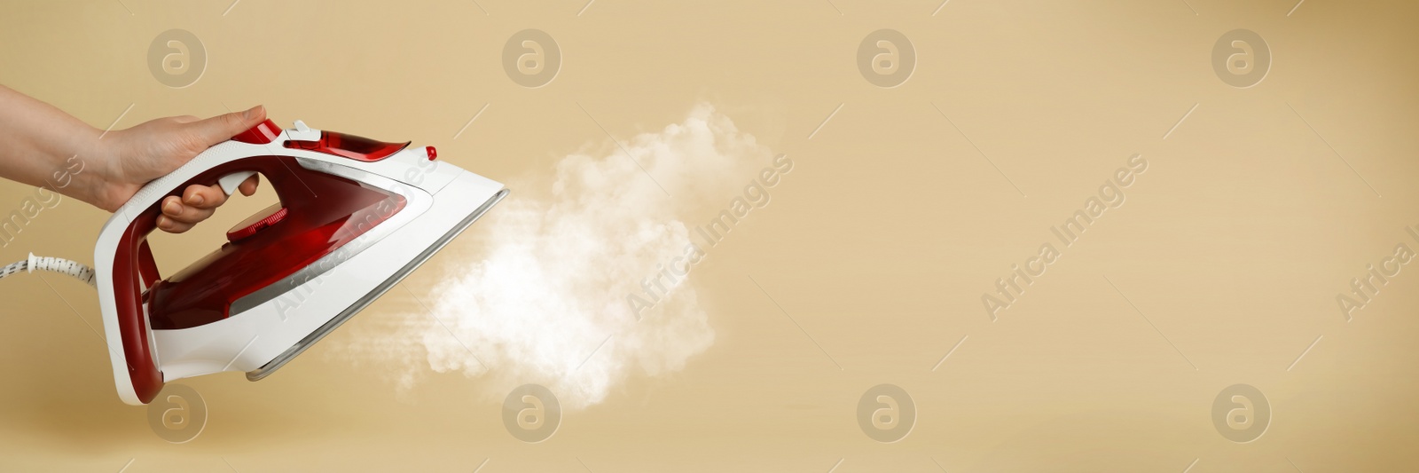 Image of Woman with iron on beige background, closeup. Banner design with space for text