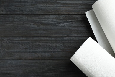 Rolls of paper towels on black wooden table, top view. Space for text