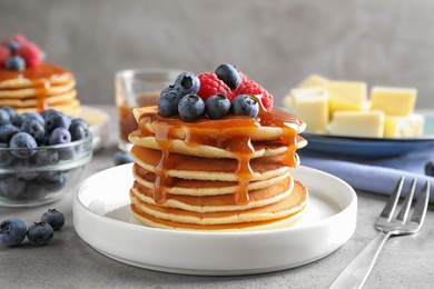 Photo of Delicious pancakes with fresh berries and syrup on grey table