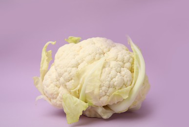 Whole fresh raw cauliflower on violet background