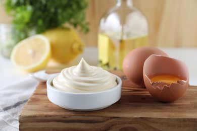 Photo of Fresh mayonnaise sauce in bowl and ingredients on table, closeup