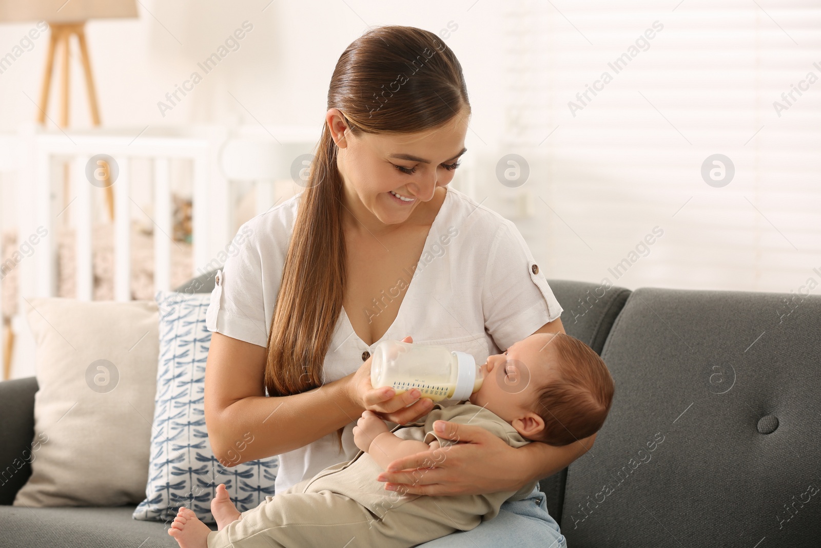 Photo of Mother feeding her cute child with infant formula indoors