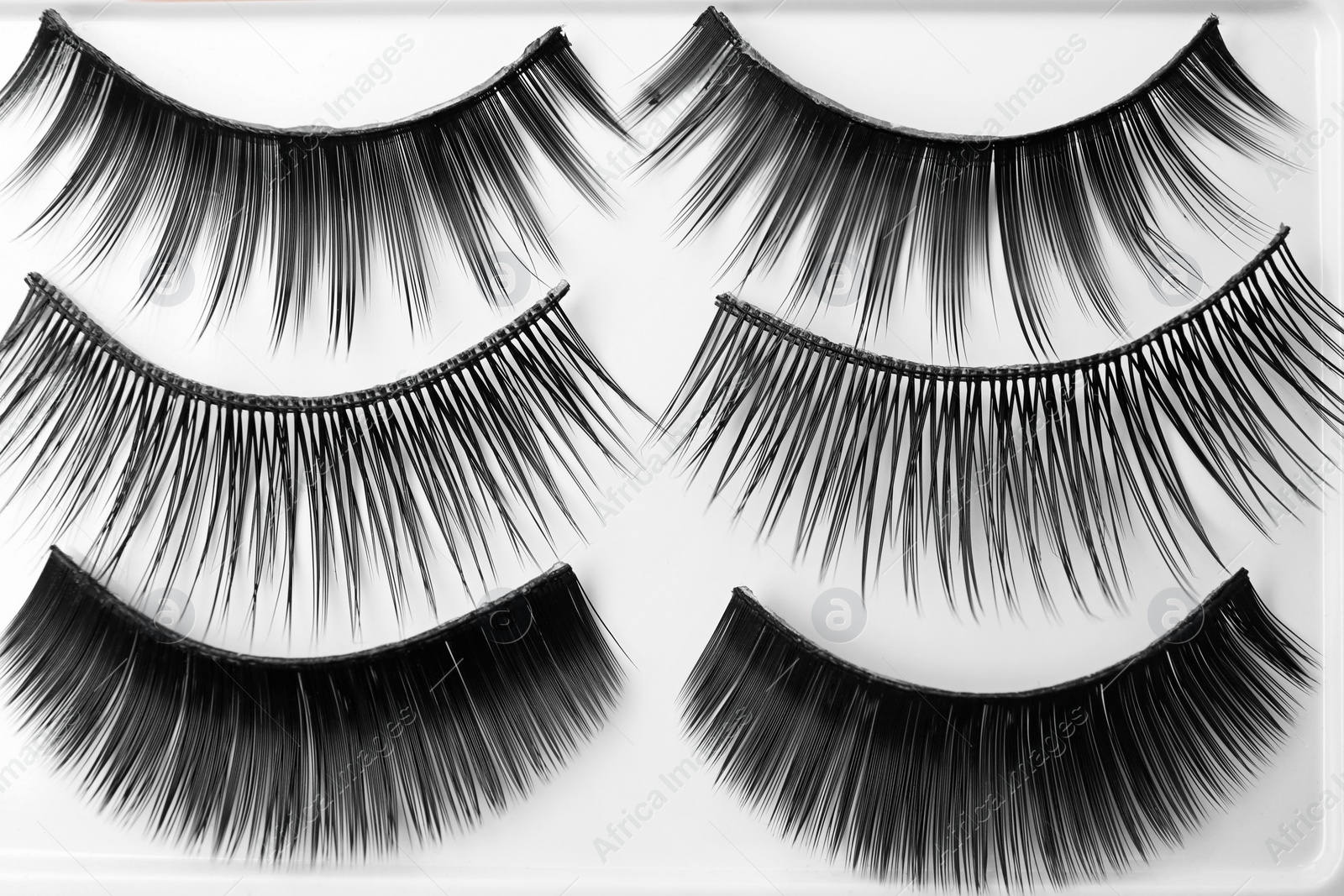 Photo of Different types of false eyelashes on light background, top view