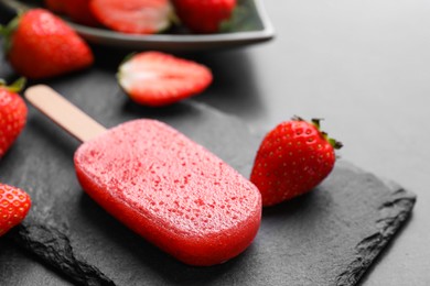 Photo of Tasty strawberry ice pop on dark table, closeup. Fruit popsicle
