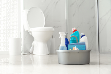 Photo of Cleaning supplies near toilet bowl in modern bathroom. Space for text