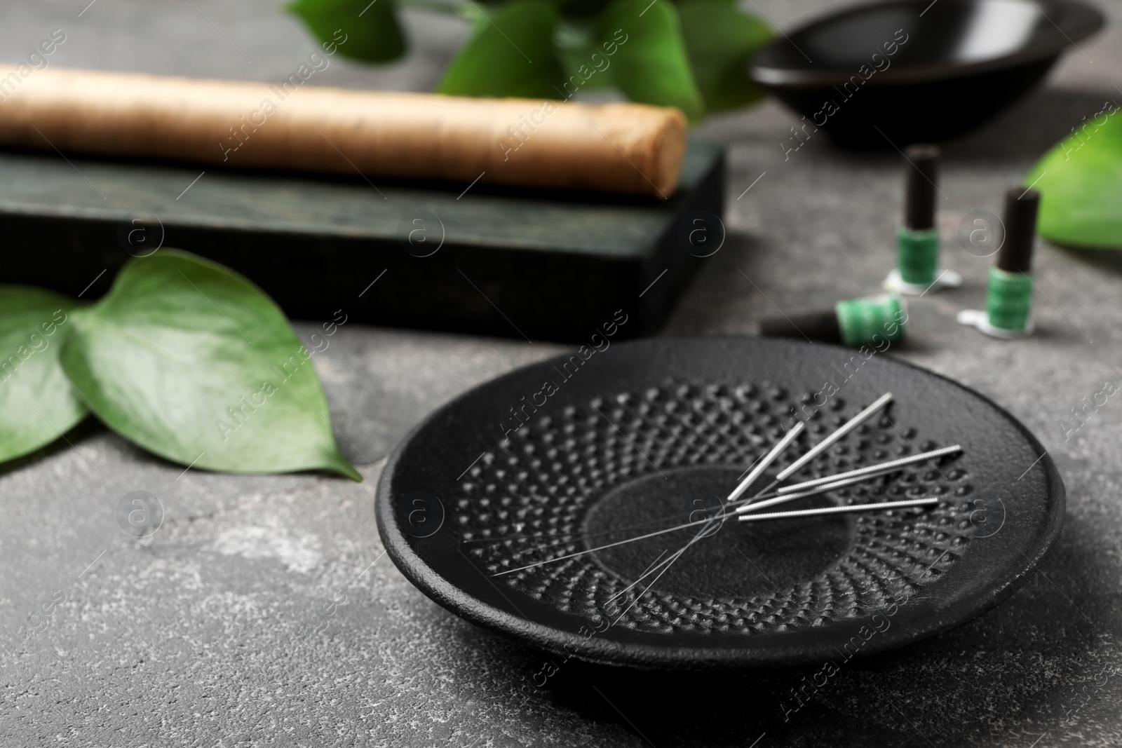 Photo of Plate with needles for acupuncture on dark table