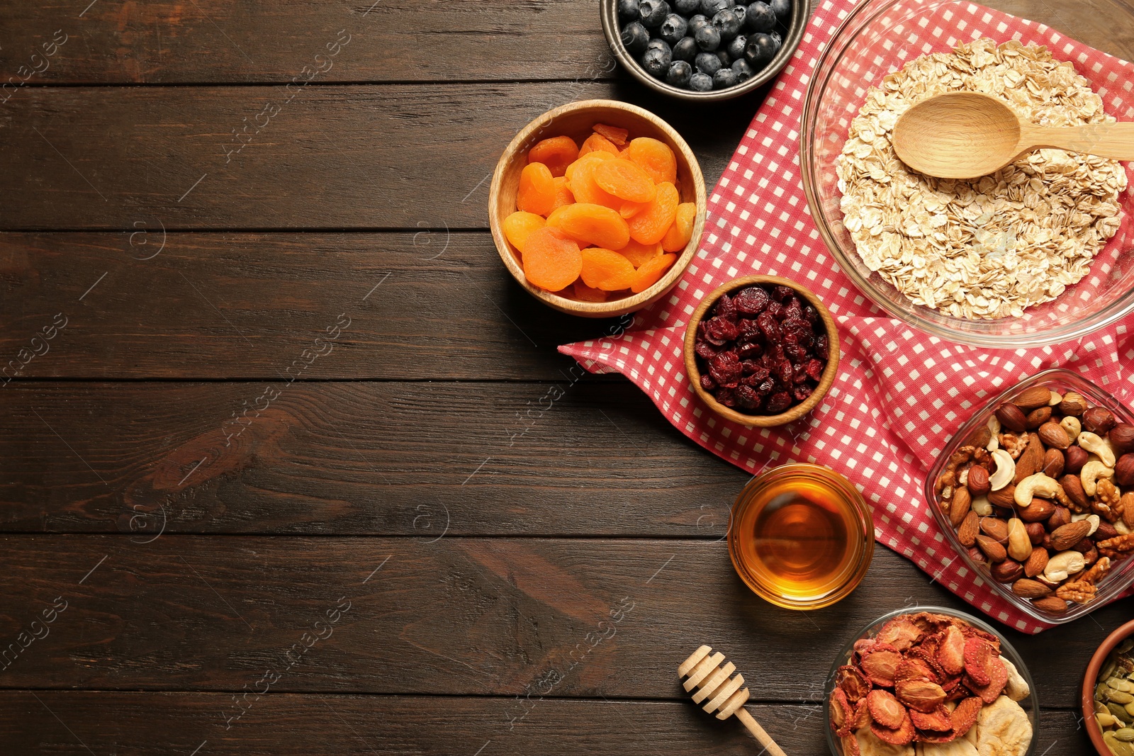 Photo of Making granola. Oat flakes, dried fruits and other ingredients on wooden table, flat lay with space for text