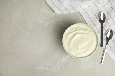 Photo of Tasty organic yogurt on grey marble table, flat lay. Space for text