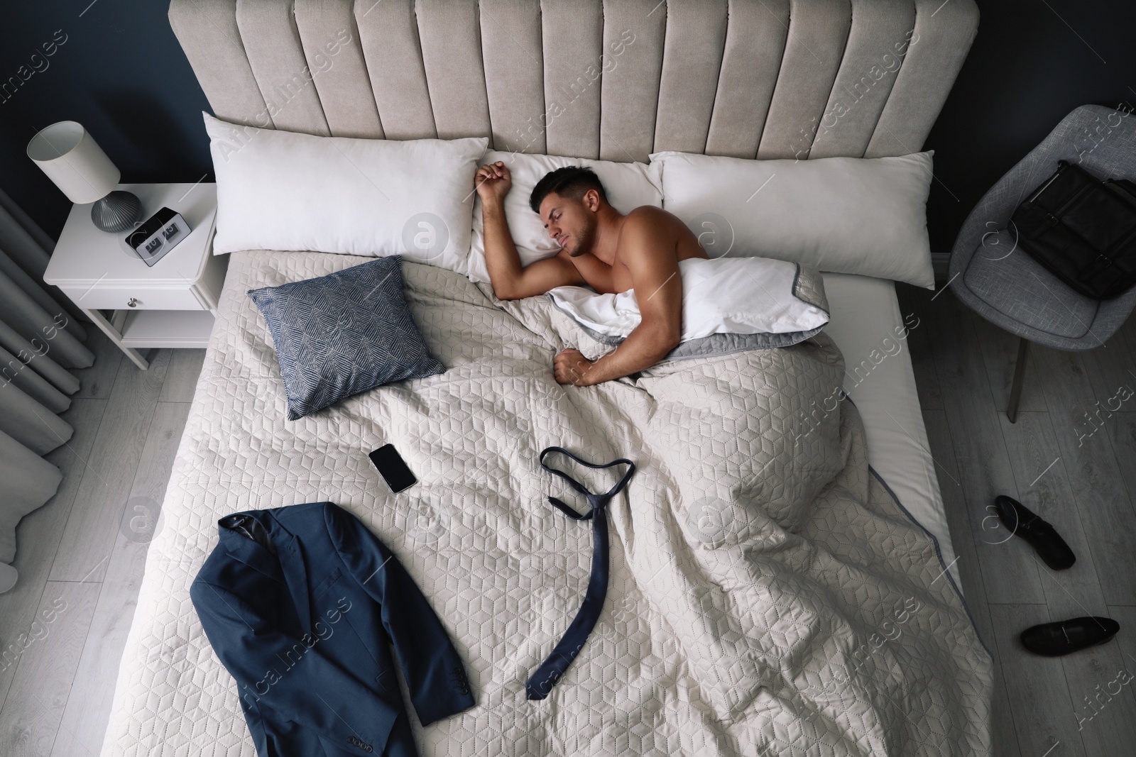 Photo of Tired man sleeping in bed at home after work, above view