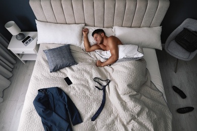 Photo of Tired man sleeping in bed at home after work, above view