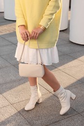 Fashionable woman with stylish bag on city street, closeup