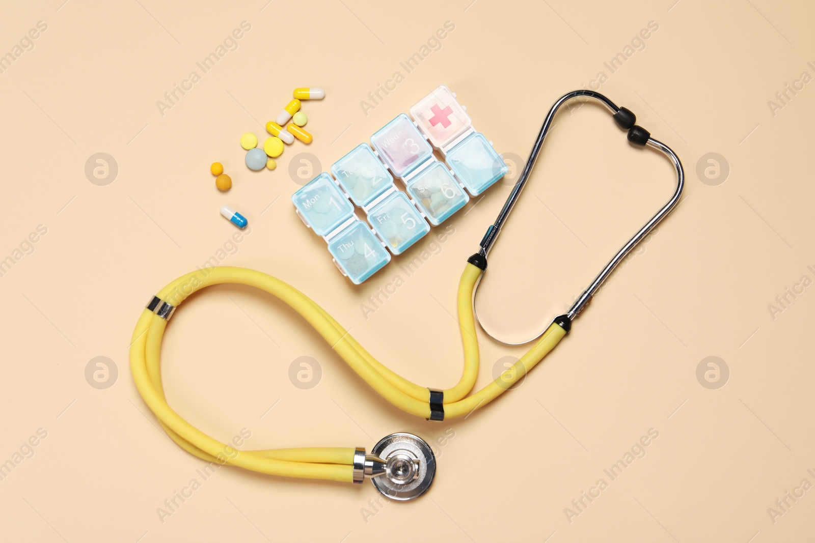 Photo of Stethoscope and pills on beige background, flat lay. Medical tool