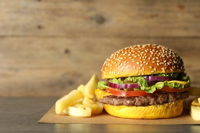 Photo of Burger with delicious patty and french fries on table, space for text