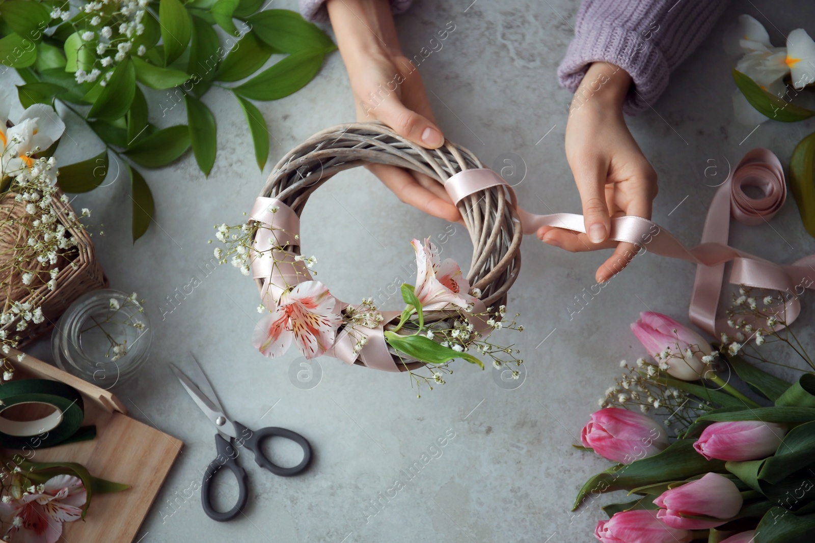 Photo of Female decorator creating beautiful wreath at table, top view