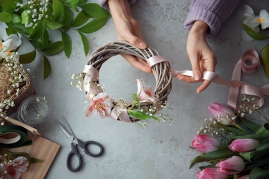 Female decorator creating beautiful wreath at table, top view