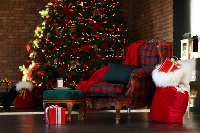Photo of Santa Claus bag near armchair in room with Christmas tree