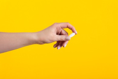 Photo of Woman holding vitamin pill on yellow background, closeup. Health supplement