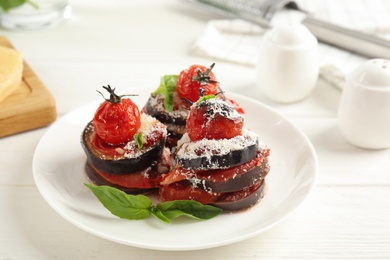Photo of Baked eggplant with tomatoes, cheese and basil served on white wooden table, closeup