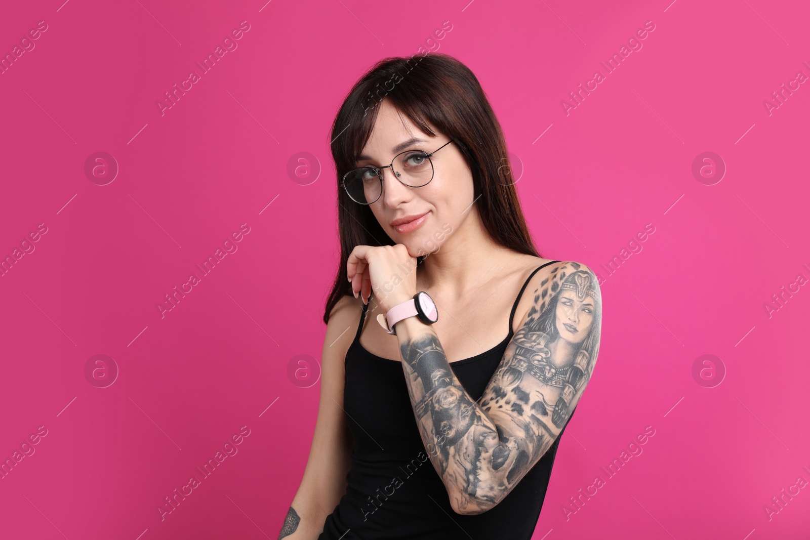 Photo of Woman with tattoos on arm against pink background