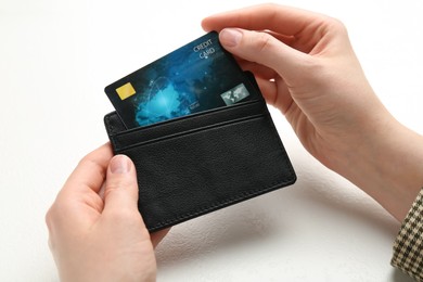 Photo of Woman holding leather card holder with credit card at white table, closeup