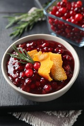 Fresh cranberry sauce, rosemary and orange peel in bowl on table, closeup