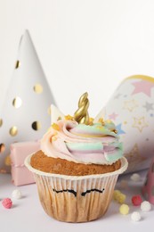 Photo of Cute sweet unicorn cupcake and party hats on white background, closeup
