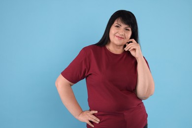 Photo of Beautiful overweight mature woman with charming smile on turquoise background 