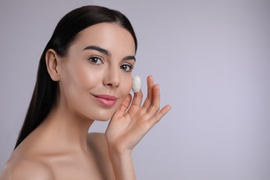 Photo of Woman using silkworm cocoon in skin care routine on light grey background. Space for text