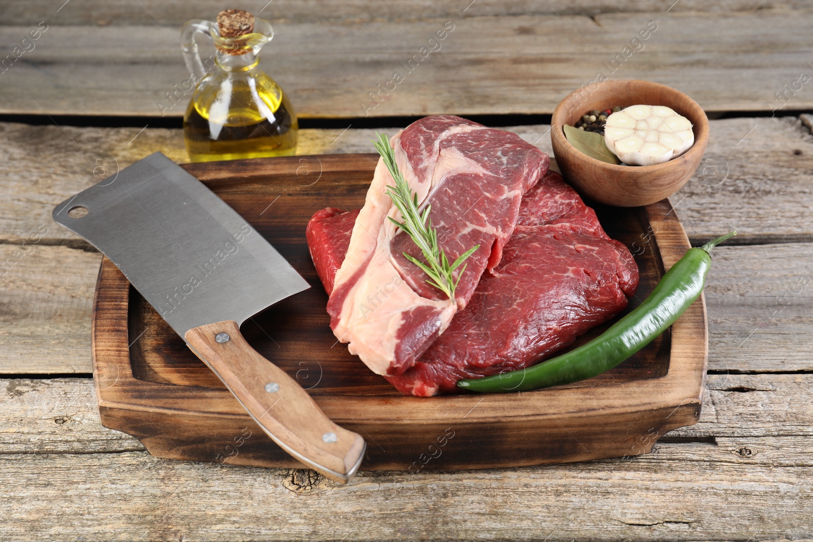 Photo of Fresh raw beef cut, spices and butcher knife on wooden table