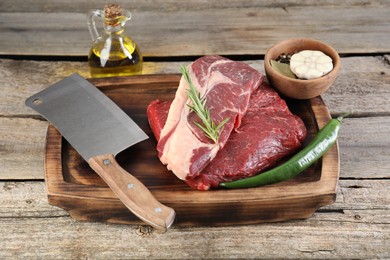 Fresh raw beef cut, spices and butcher knife on wooden table