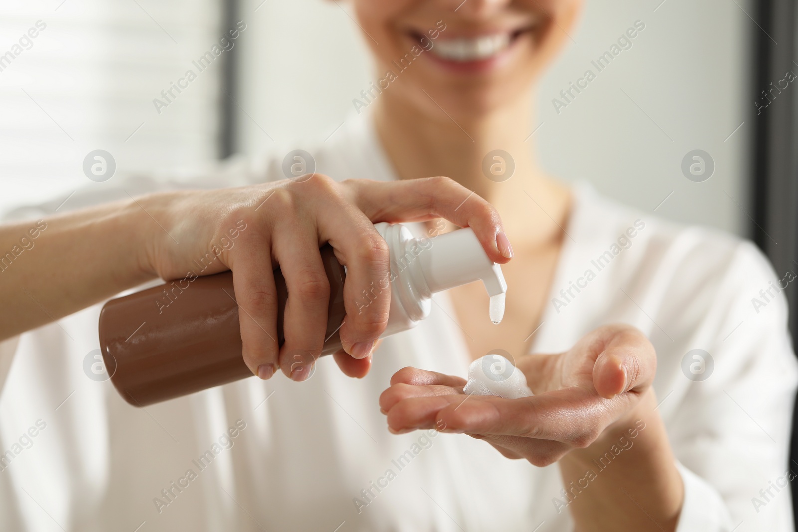 Photo of Woman applying self-tanning product onto hand indoors, closeup