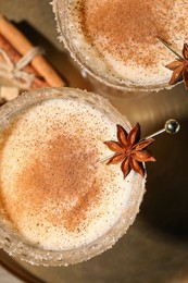 Photo of Delicious eggnog with cinnamon and anise on wooden table, flat lay
