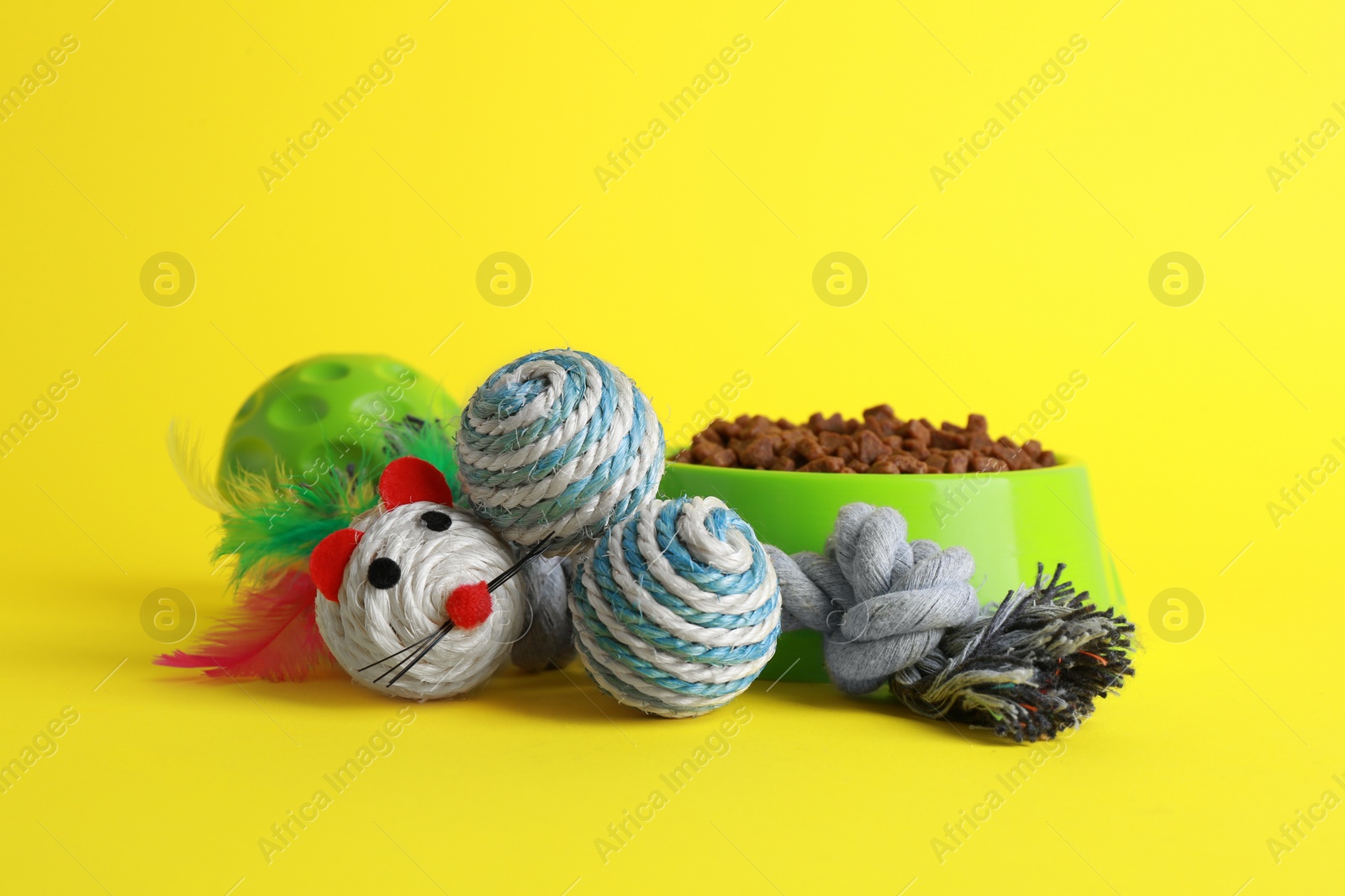 Photo of Pet toys and feeding bowl on yellow background