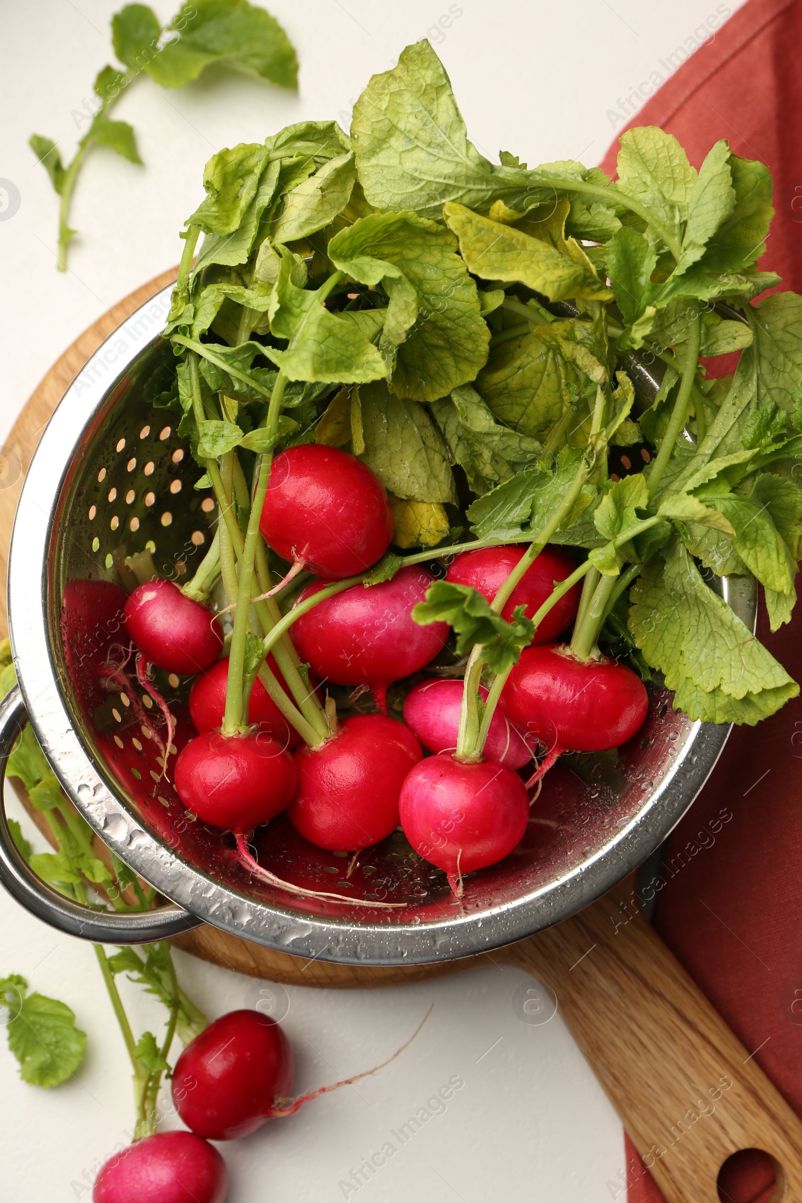 Photo of Wet radish in colander on white table, flat lay