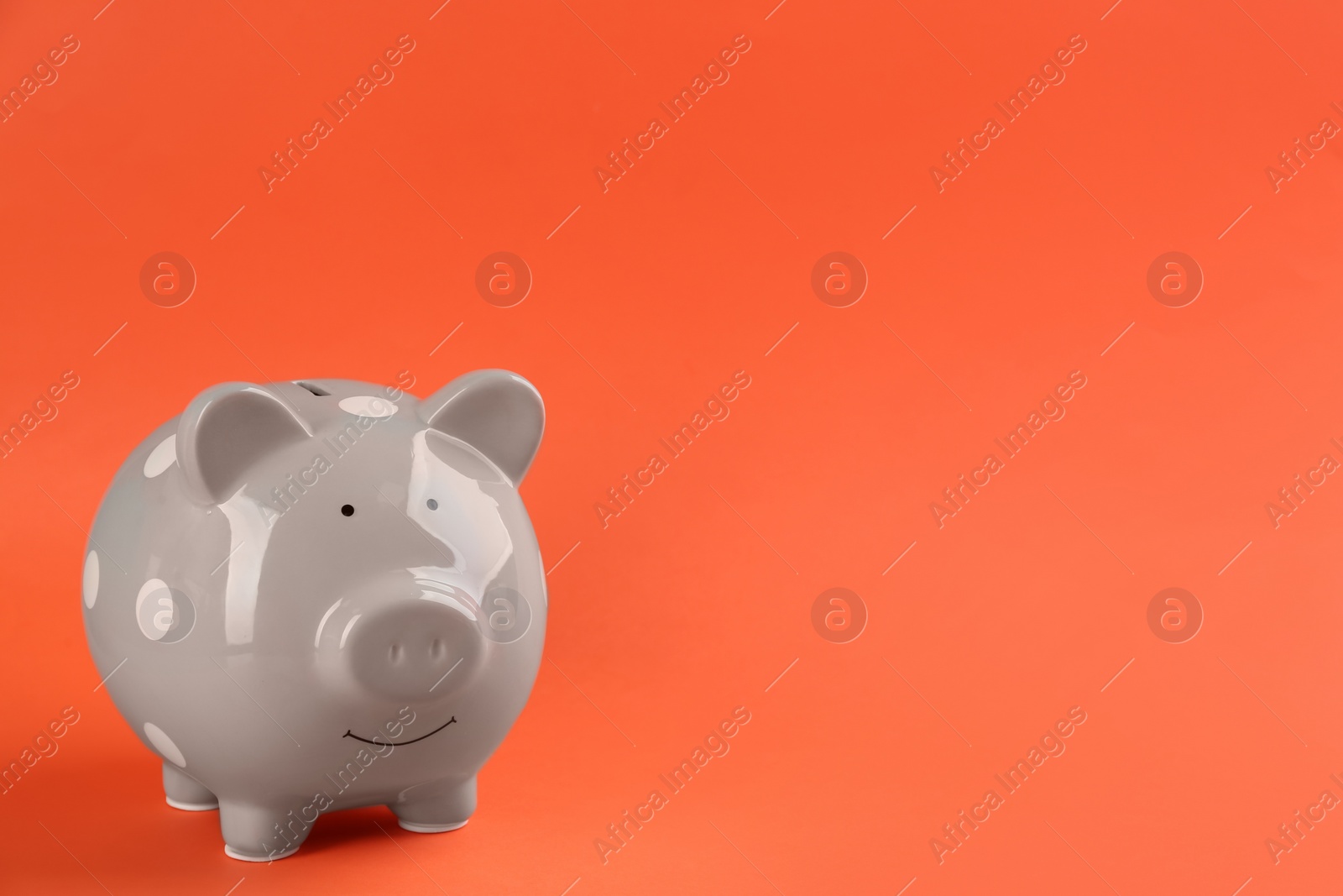 Photo of Grey piggy bank on orange background. Space for text