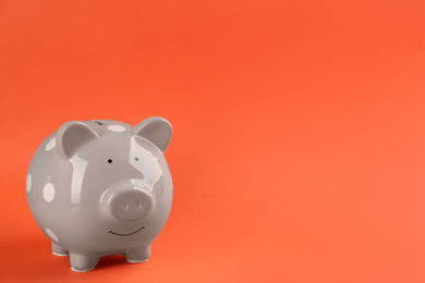 Photo of Grey piggy bank on orange background. Space for text