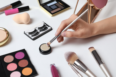 Photo of Beauty blogger taking eyeshadow with brush at table, closeup