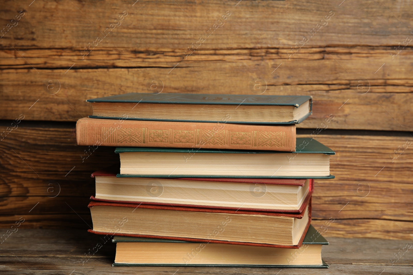 Photo of Collection of different books on table against wooden background
