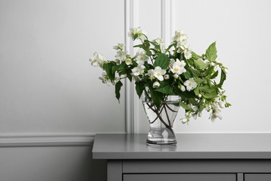 Photo of Beautiful bouquet with fresh jasmine flowers in vase on grey table indoors