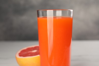 Tasty grapefruit juice in glass and fresh fruit on white table, closeup