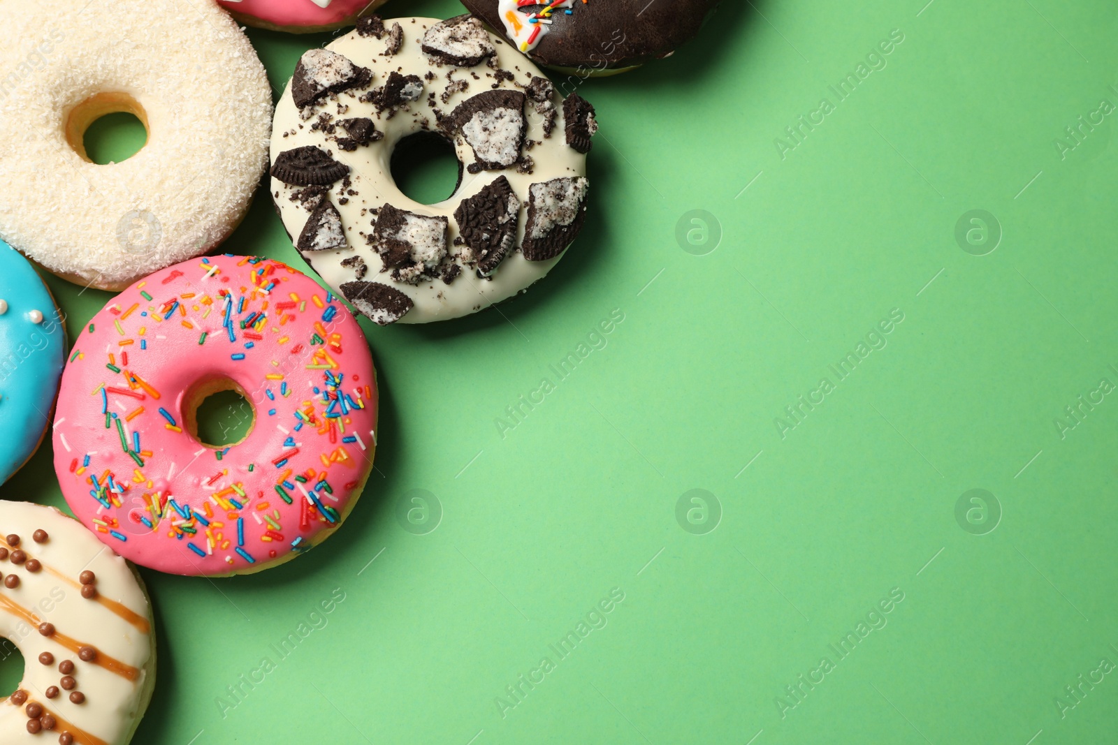 Photo of Sweet tasty glazed donuts on green background, flat lay. Space for text