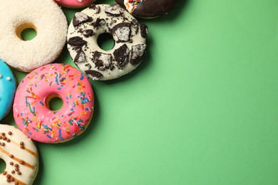 Sweet tasty glazed donuts on green background, flat lay. Space for text