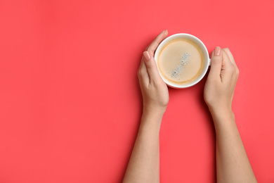 Photo of Woman with cup of coffee on red background, top view. Space for text