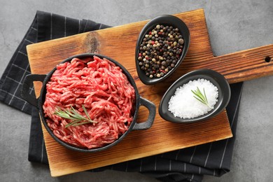 Raw ground meat in bowl and spices on grey table, top view