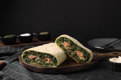 Photo of Tasty strudel with salmon and spinach on black wooden table