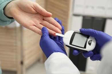 Diabetes. Doctor checking patient's blood sugar level with glucometer in clinic, closeup