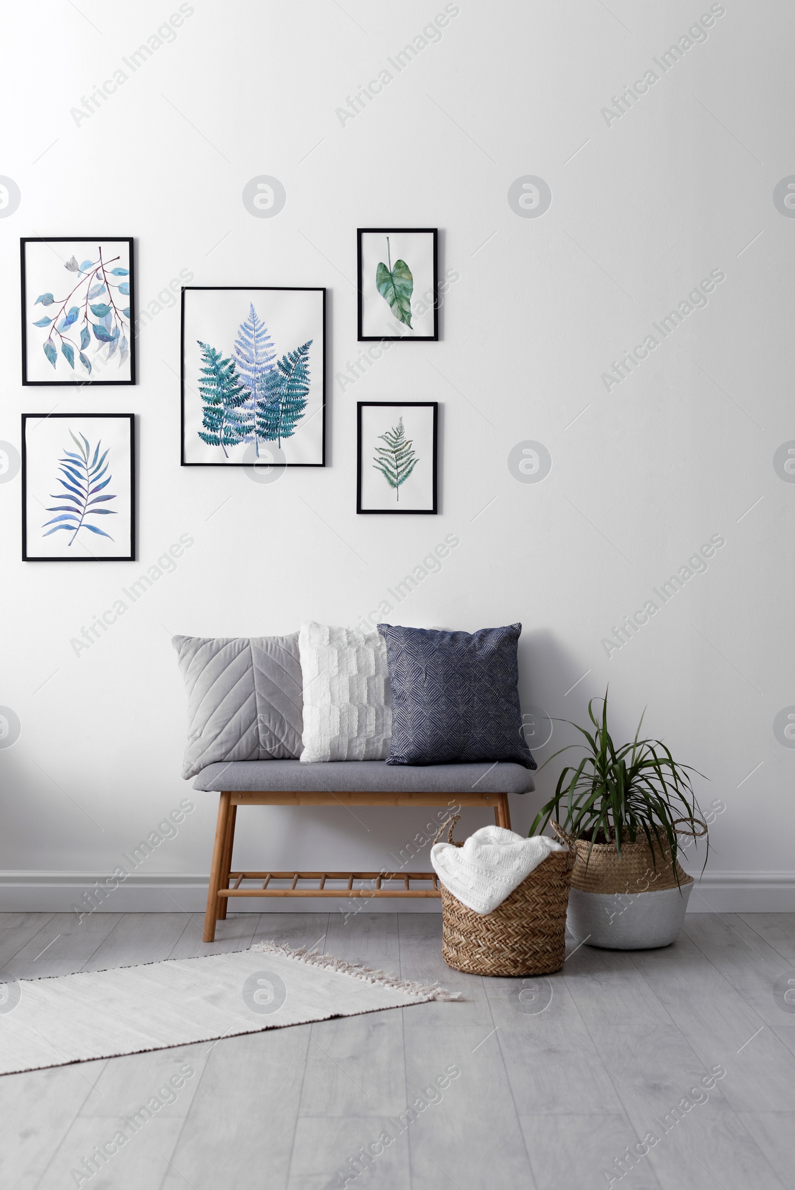 Photo of Beautiful paintings of tropical leaves on white wall in living room interior