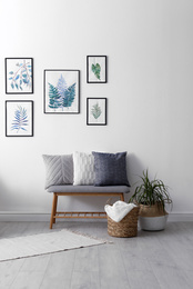 Photo of Beautiful paintings of tropical leaves on white wall in living room interior